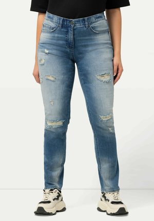 Svetle modré skinny džíny vyrobené z denimové látky, se stylovými oděrkami, trhanými detaily a klasickým pětičetným designem, doplněné teniskami.