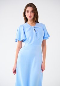 Himmlisches blaugraues Kleid mit luftigen Ärmeln, einem Schlüsselloch-Ausschnitt und einem fließenden Rock. Glatte Stoffstruktur mit tailliertem Schnitt.