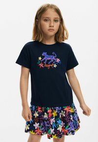 Tricou navy cu un tigru ilustrat colorat și flori, asociat cu o fustă evazată împodobită cu modele florale strălucitoare.