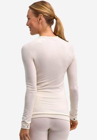 Maglietta leggera a maniche lunghe in un tessuto crema testurizzato, caratterizzata da un design aderente e accenti a contrasto ai polsini.
