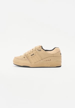 Zapatillas deportivas beige de cuero, con una superficie texturizada, diseño de tres rayas, cierre de cordones y detalles en negro en la suela.