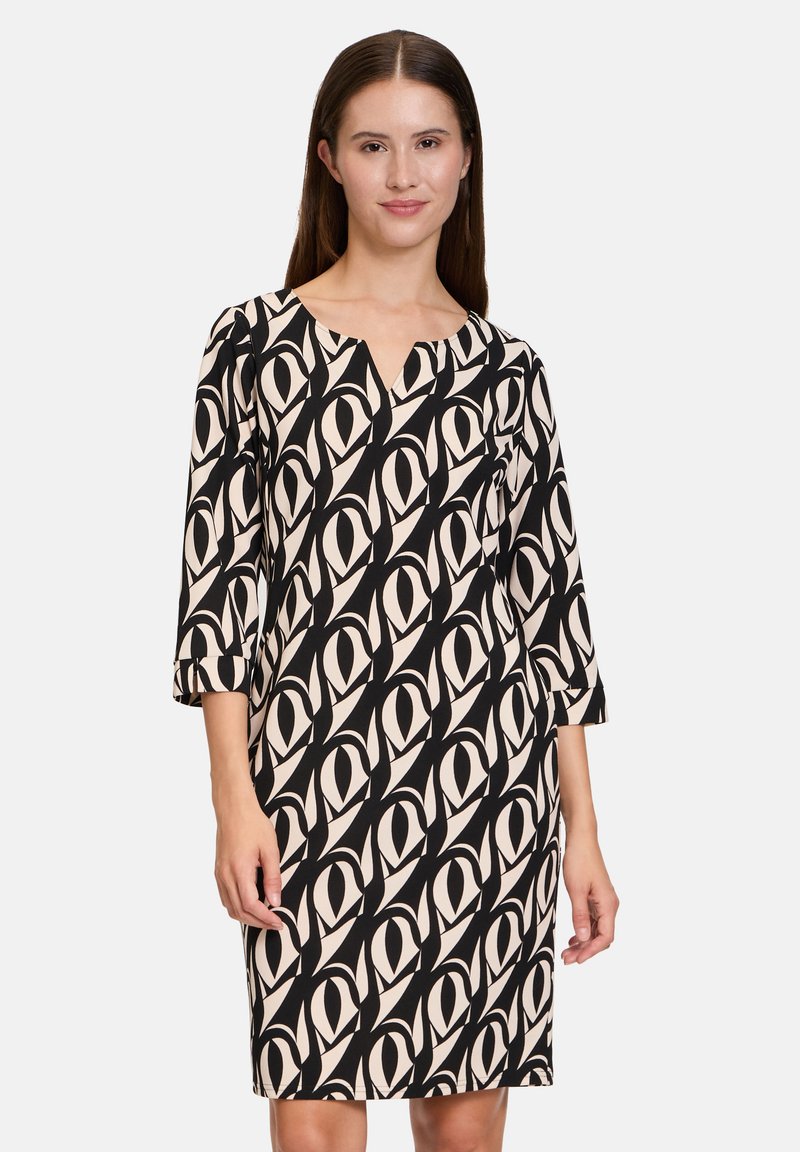 Schwarz-beiges gemustertes Kleid mit drei Viertelärmeln, V-Ausschnitt und lockerem Schnitt, das ein geometrisches Augendesign aufweist.