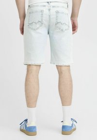 Ljust blå denimshorts med rak skärning, fransad nederkant och två bakfickor med zigzag-sticksömnad. Tillsammans med blå skor.
