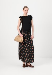 Čierny top s krátkym rukávom a volánmi, spárovaný s maxi sukňou s kvetinovým vzorom. Béžová kabelka a tmavohnedé loafers dopĺňajú vzhľad.