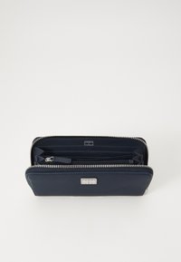 Portafoglio in pelle blu navy con accessori in argento, chiusura zip, più scomparti per carte e un compartimento con zip per monete o banconote. Texture liscia.