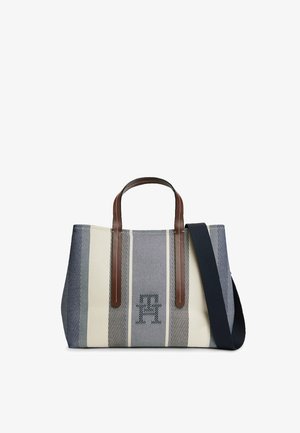 Płócienna torba na ramię w paski: granatowe i kremowe pionowe paski, brązowe skórzane uchwyty oraz odpinany szeroki granatowy pasek na ramię.