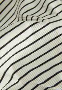 Tissu rayé en crème avec des rayures horizontales noires, présentant une texture côtelée. Les rayures varient en épaisseur sur le matériau.