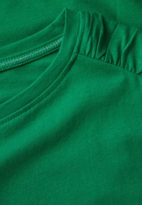 Grøn bomulds T-shirt med rund halsudskæring og samlet detalje på skulderen. Glat tekstur med fint ribbet stof.