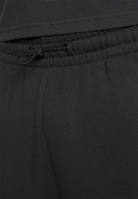 Schwarze Jogginghosen aus weichem Stoff mit elastischem Bund und verstellbarem Kordelzug. Verfügt über eine glatte Textur und eine enganliegende Passform.
