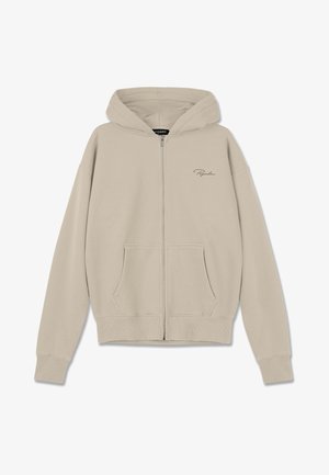 Corta-vento bege com fecho, feito de material suave, apresentando um capuz com cordão, dois bolsos frontais e um discreto bordado de logo no peito.