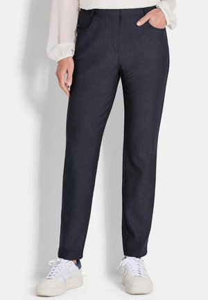 Pantaloni blu navy con una texture liscia, taglio dritto, tasche laterali e una lucentezza sottile. Abbinati a sneakers bianche per un look casual.