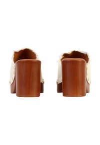 Paire de sabots blancs à enfiler avec talons blocs en bois et bords effilochés, vus de dos sur fond blanc.