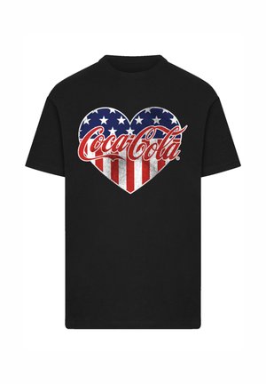 Black t-shirt featuring a heart design in red, white, and blue with stars and stripes, and the Coca-Cola logo in a stylized font.