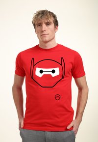 Camiseta de algodón roja con un gráfico de cara de robot en contorno negro en la parte delantera, textura suave, cuello redondo y mangas cortas.
