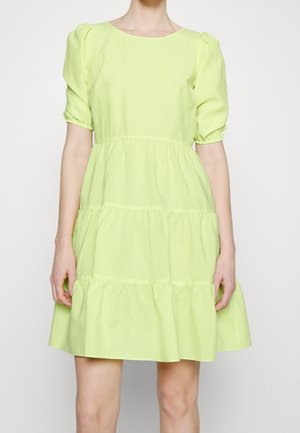 Robe courte verte à manches courtes en tissu léger. Présente un col rond, des volants superposés à l'ourlet et des manches bouffantes froncées.