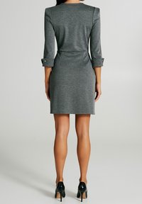 Szara sukienka do kolan z rękawami o długości trzech czwartych, okrągłym dekoltem i guzikami przy mankietach. Materiał wygląda na gładki i lekko rozciągliwy.