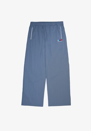 Niebieskie spodnie z elastycznym pasem, białymi suwakami kieszeni oraz małym czerwono-biało-niebieskim logo z napisem "PROHIBITED" po prawej stronie.