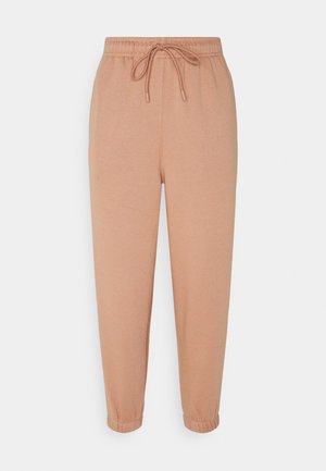 Pantalon de survêtement beige avec taille élastique, cordon de serrage et poignets aux chevilles, présenté sur un fond clair uni.