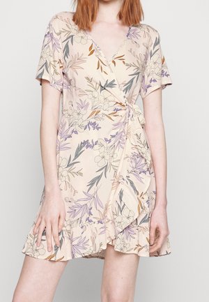 Vestido envolvente floral de tela melocotón claro, con mangas cortas, un escote en V profundo y un dobladillo con volantes adornado con impresiones botánicas en púrpura y verde.