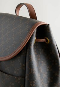 Sac à dos en cuir brun avec une surface noire texturée, présentant un motif en relief, un contour brun et des accents en métal doré.