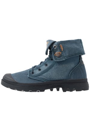 Niebieskie wysokie buty z płótna z czarną gumową podeszwą, sznurowane z przodu, złożony kołnierz z detalem w postaci guzika oraz teksturowaną bieżnią zapewniającą przyczepność.