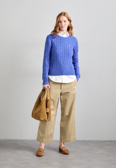 Sinine nöörkootud sviiter, valge kraega särk all, beež laiad püksid, pruunad nahast mokassiinsandaalid ja pruun nahktootekott.