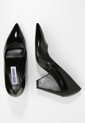 Paire de chaussures noires en cuir verni à bout pointu et talon bloc, l’une vue de dessus et l’autre de côté.