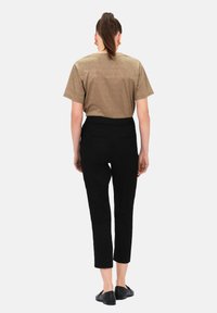 Czarne krótkie spodnie z dopasowaną talią, połączone z błyszczącą miedzianą bluzką z krótkim rękawem, widziane z tyłu. Gładka tekstura materiału.