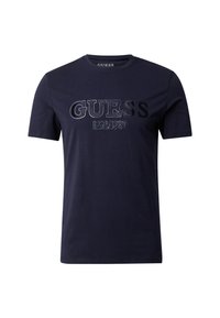 Camiseta de algodón azul marino de manga corta, con un logotipo texturizado "GUESS EST.1981" en un tono más oscuro que contrasta en el pecho.