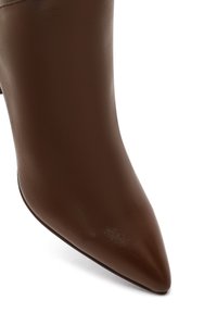 Bottes en cuir marron à bout pointu avec une texture lisse et un design épuré et minimal. Présentent un talon élancé et une silhouette propre et simple.