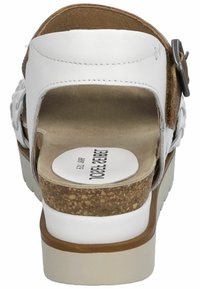 White leather sandal with a cork footbed, adjustable buckle, and textured sole. Open back design with a smooth finish and padded insole.