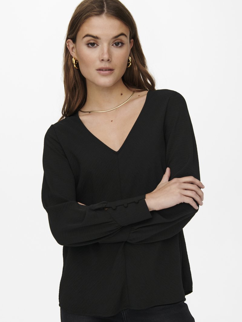 Blusa preta de manga longa com decote em V, em tecido texturizado, com detalhes em botões nos punhos, combinada com uma silhueta suave e ajustada.