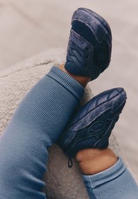 Sneakers in tessuto blu scuro con pannelli in rete strutturata e suole di gomma, abbinati a leggings azzurri a coste.