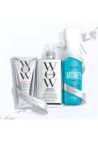 Drie haarproducten: een zilveren tube shampoo, een doorzichtige spuitfles gelabeld "Dream Coat," en een blauwe fles gelabeld "Money Mist," met witte linten.