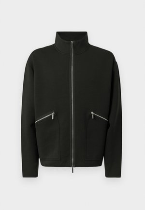 Crna jakna na patent s visokim ovratnikom, dva džepa s patentnim zatvaračima sprijeda, izrađena od mekog tkanja, s jednostavnim, modernim dizajnom.