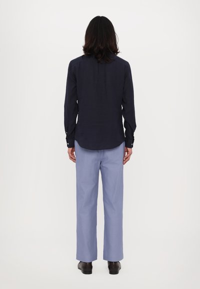 Tricou cu mânecă lungă bleumarin, pantaloni largi de culoare albastru deschis, pantofi negri, material neted, croială standard, detalii cu nasturi vizibile pe mâneci.