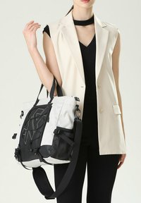 Grande borsa a tote bianca e nera, realizzata in tessuto resistente, con tracolla regolabile, tasche laterali in rete e un design del logo ben visibile.