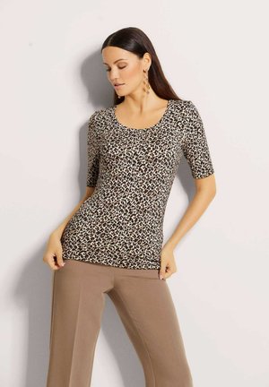 Leopardenmuster Kurzarmoberteil mit Rundhalsausschnitt in Beige- und Brauntönen, mit einer figurnahen Passform. Kombiniert mit beigen Hosen.