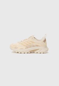 Beige Trailrunning-Schuh mit einem Obermaterial aus Mesh, strukturierten Akzenten, erhöhtem Sohlenprofil für Grip und dezentem Branding an der Seite.