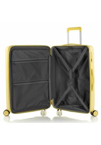 Valigia rigida gialla con manico telescopico argentato, quattro ruote e interni grigi dotati di tasche in rete con zip e cinghie incrociate.
