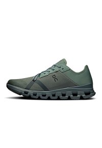 Groene sportieve schoenen met een bovenwerk van mesh, een textuur overlay en een contrasterende donkergrijze zool. Voorzien van veters en een logo aan de zijkant.