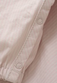 Ljust rosa tyg med tunna ränder, med en knapp med ett ringhål och rynkad sömnad för textur och detalj.