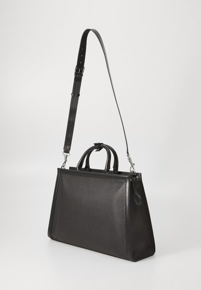 Schwarze Lederhandtasche in rechteckiger Form mit doppelten Obergriffen und verstellbarem, abnehmbarem Schultergurt, auf einer weißen Fläche aufrecht stehend.