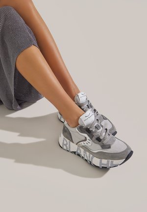 Zapatillas grises que combinan materiales de malla y ante, con punta redondeada, cordones planos y un audaz texto "BLANC" en la suela.