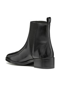 Botte chelsea noire en cuir avec des panneaux élastiques sur les côtés, texture lisse, bout rond, et talon bloc bas. Dotée d'une languette pour un enfilage facile.