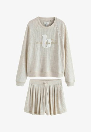 Beige-värinen, waffle-kuvioitu, pitkähihaisen collegepuseron, jossa "b by Ted Baker" -logo, ja siihen sopiva laskostettu nyörimekko.