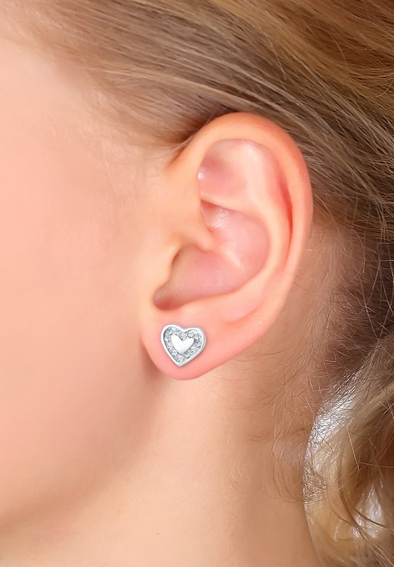 Heart-shaped earrings feature a silver outline with a small heart at the center, surrounded by clear, sparkling stones.