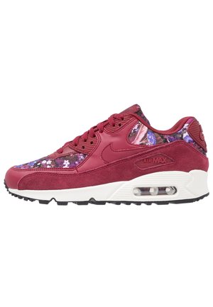 Rød Nike Air Max sneakers med lavt snit, blomstret stofpaneler, hvid mellemsål med synlig luftstød, og sort gummiydersål.