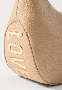 Borsa a tracolla in ecopelle beige con superficie testurizzata. Lettere dorate "LOVE" esposte in modo prominente sul lato, con una finitura liscia attorno ai bordi.