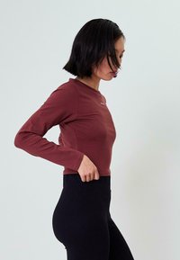 Kerge materjalist tumepeenuse pikkade varrukatega top, millel on ümmargune kaelus ja sobiv disain, kombineerituna mustade kõrge vöökohtadega legginsitega.